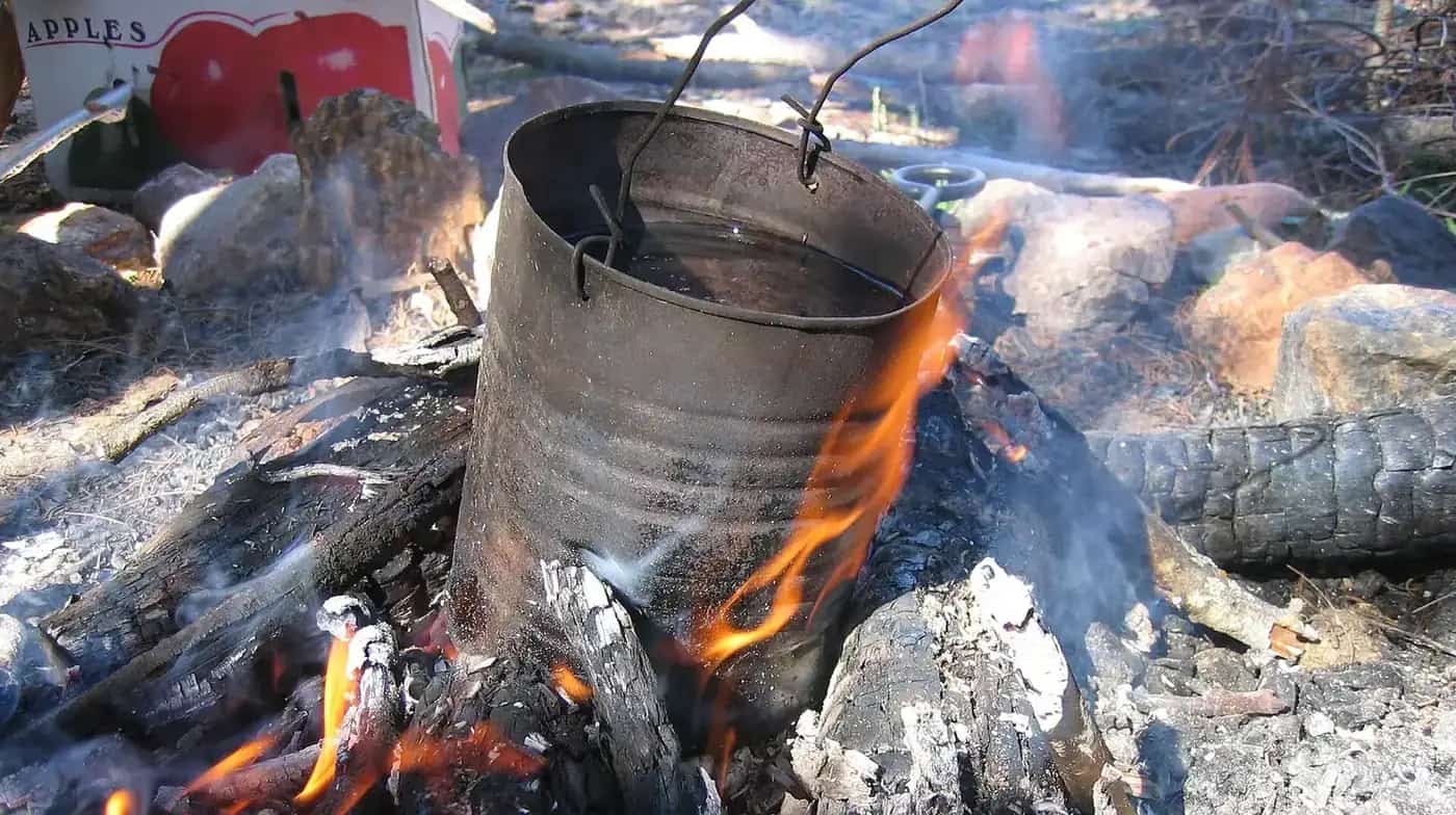 A billycan boiling on a campfire